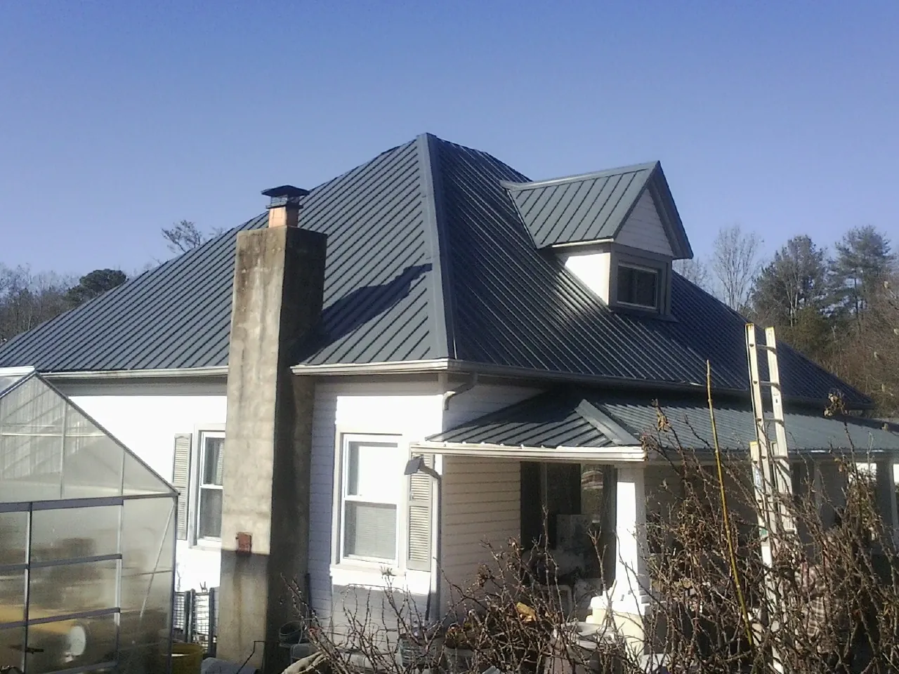 Dark blue standing seam metal roof on a white farmhouse with dormer — Slate & Tile Roof Repair by Roofing Brothers in Maybee