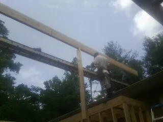 Carpenter setting a ridge beam over a new addition frame — Ice Dam Removal by Roofing Brothers in Maybee