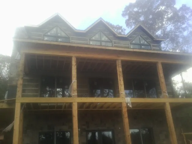 Dormers and porch framing on a large log home under construction — Roof Coating work by our crew in Maybee