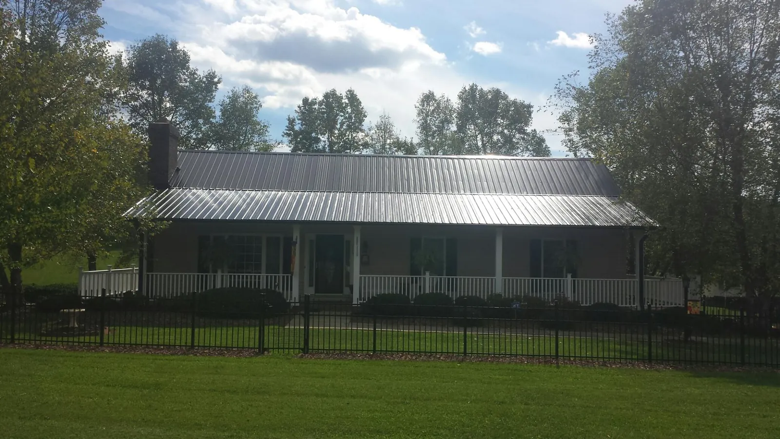 Gray metal roof on a brick ranch with a full width front porch — Gutter Guard Installation work by our crew in Maybee