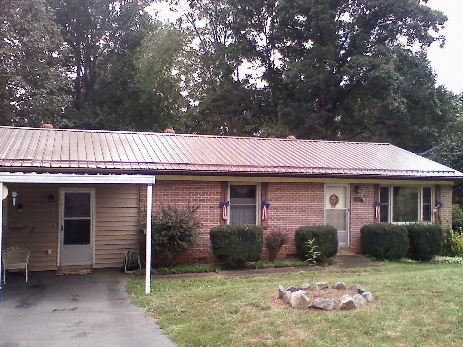 Bronze metal roof and carport on a brick ranch home — Roof Repair work by our crew in Maybee