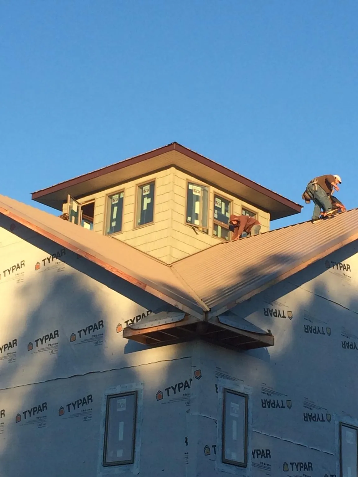 Roofers working around a rooftop cupola on a new metal roof at sunset — Roof Waterproofing in Maybee by Roofing Brothers